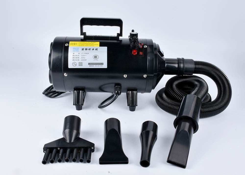 Pink metal dog hair dryer with black hose and four nozzle attachments on white background