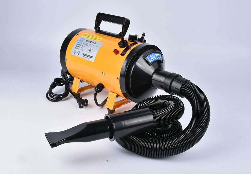 Pink metal dog hair dryer with black hose and four nozzle attachments on white background