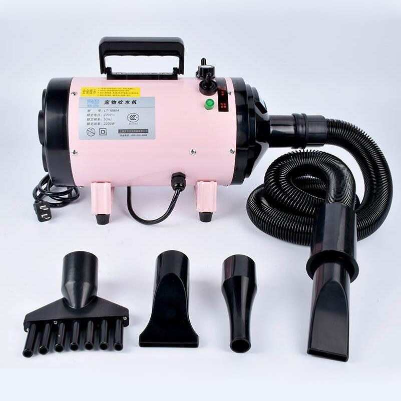 Pink metal dog hair dryer with black hose and four nozzle attachments on white background