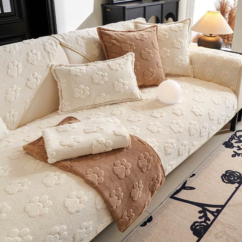 Thickened fleece cream plush non-slip sofa cover with paw print texture and matching cushions on a modern sofa
